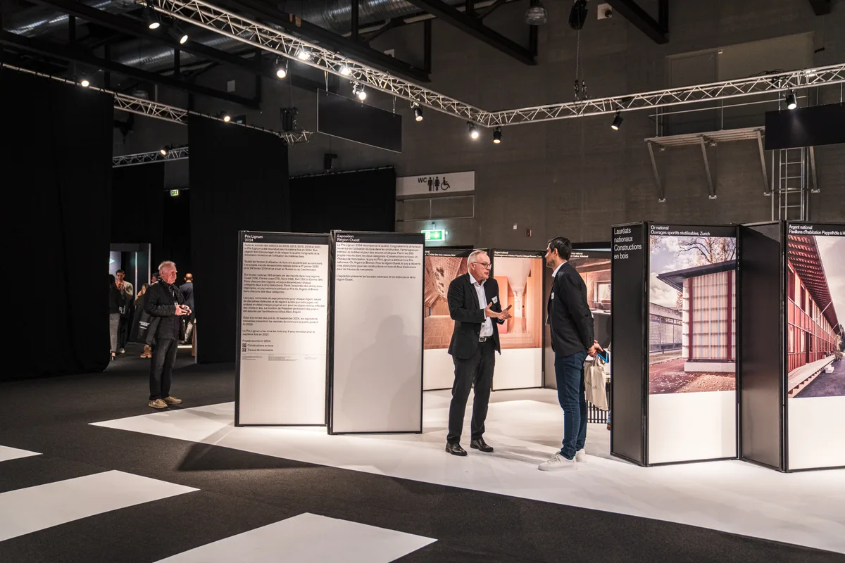 Visiteurs devant les panneaux d'exposition du salon